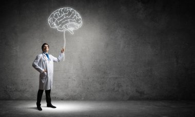 Arka planda gri Duvar ile boş oda içinde ayakta beyin beyaz parlayan sembolü ile interracting beyaz tıbbi takım genç erkek doktor kavramsal görüntü.