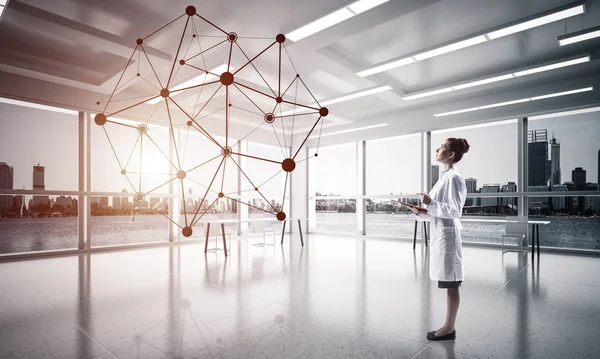 Confident medical industry employee standing inside white hospital building and examining black network structure. Modern technologies for medical industry