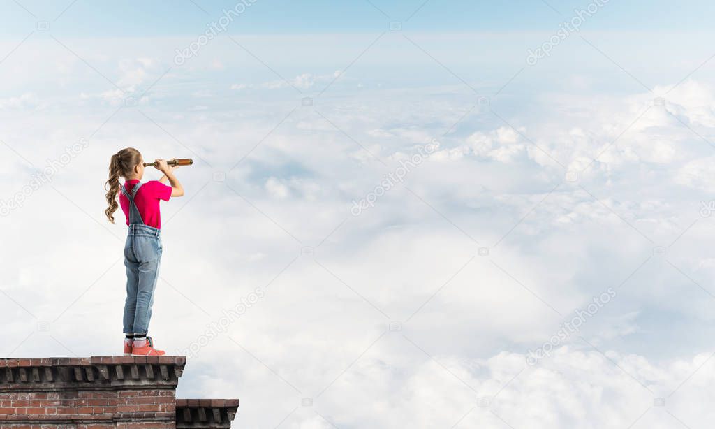 Cute kid girl standing on house roof and looking in spyglass