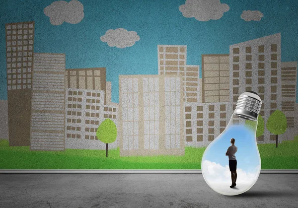 Businesswoman inside light bulb against city drawn concept