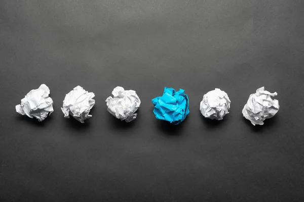 Pelota de papel azul arrugada entre bolas blancas — Foto de Stock