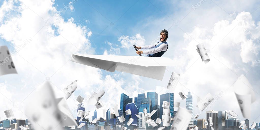 Business accounting and statistics concept with funny pilot. Aviator driving paper plane above falling paper sheets with infographics. Young man flying in paper airplane above paperwork.