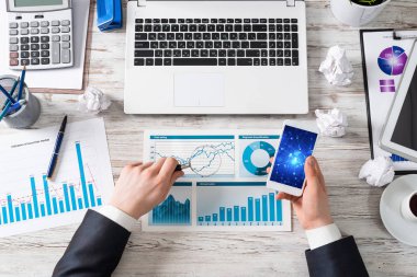 Ofis masasında akıllı telefon kullanan işadamı