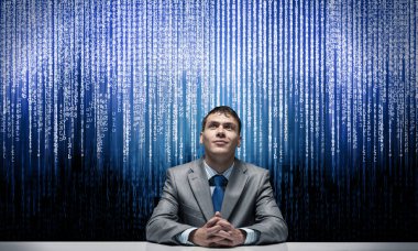 Gülümseyen adam ellerini katlayıp yukarı bakıyor. İş süreci için yapay zeka teknolojisi. Mutlu bir iş adamı masada oturuyor. İş elbisesi adam ve dijital veri akışı arka plan üzerinde kravat.
