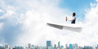 Megapolis'in üstünde kağıt uçak kullanan havacı. Kağıt düzlemde oturan ve direksiyon u tutan pilotun yan görünümü. Yüksek gökdelenler ve ofis binaları ile Cityscape. Karma medya iş kavramı