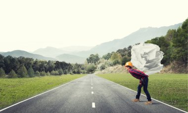 Sırtında kağıt top taşıyan inşaatçı.