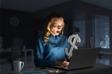 Parlak dizüstü bilgisayar ekranına bakan güzel bir kız. Karışık ortam