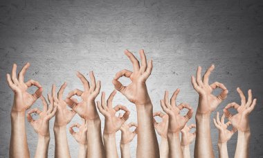 İyi bir jest gösteren bir sıra adam eli. Anlaşma ve onay işareti grubu. İnsan elleri gri duvarın arka planında siler. Birçok kol birlikte kaldırdı ve mevcut popüler jest.