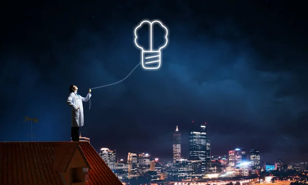 Professional medical industry employee in white medical suit interracting with glowing screw symbol in the air while standing on brick roof and night sky view on background.