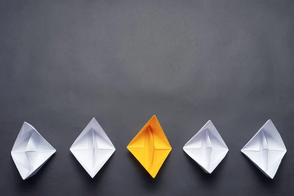 Row of paper ships on black background