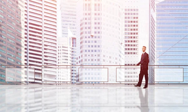 Gökdelenlerin üzerinde gün doğumu ve yeni bir güne bakan iş adamı