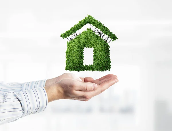 Myšlenka na bydlení nebo hypotéku se zeleným symbolem domu v mužských dlaních. Kombinovaná média — Stock fotografie