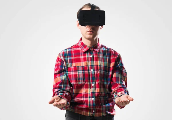 Young man in checked shirt wearing virtual helmet against gray background