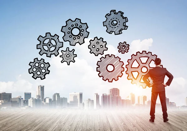 Modern şehre bakan ve vites düzeneği çizen işadamlarının arka planı