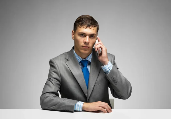 Young Man Talking Phone Looking Camera Businessman Sitting Desk Grey — Stock Photo, Image