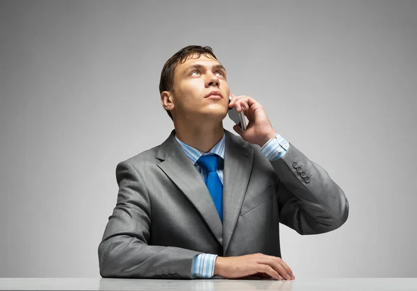 Young Man Talking Phone Looking Upward Businessman Sitting Desk Grey Royalty Free Stock Photos