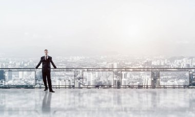 Gökdelenlerin üzerinde gün doğumu ve yeni bir güne bakan iş adamı