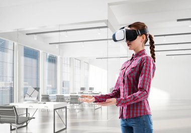 Modern ofis içinde sanal gerçeklik kaskı takan genç bir kadın. Karışık ortam