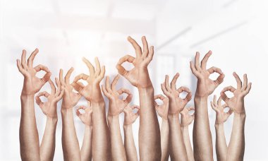 Row of man hands showing okay gesture. Agreement and approval group of signs. Human hands gesturing on light blurred background. Many arms raised together and present popular gesture. clipart