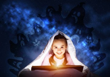 Mutlu küçük kız uyumadan önce yatakta kitap okuyor. Battaniyenin altında el feneri saklanan bir çocuk. Pijama ve komik hayaletler gece gökyüzünde geri gülümseyen kız. Çocuk okuma sihirli peri masalları.