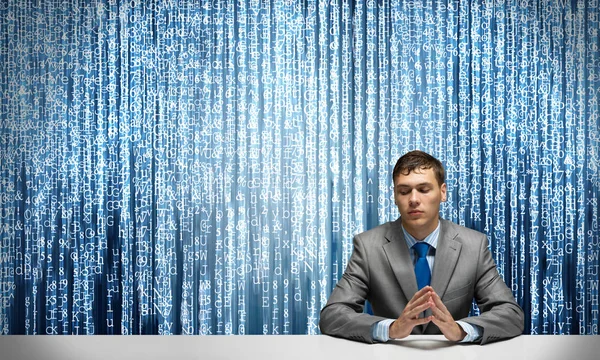 若い真面目な男は手を組んで机に座っていた デジタル技術とオンラインデータストリーム ビジネスマンの肖像画は ビジネススーツを着用し バイナリマトリックスコードの背景にネクタイ 機械学習 — ストック写真
