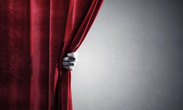 Concrete wall behind drapery curtain and hand opening it — Stock Photo, Image