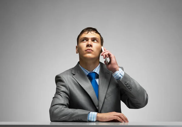 Young Man Talking Phone Looking Upward Businessman Sitting Desk Grey Stock Picture