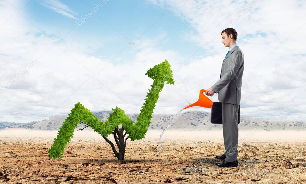 Businessman watering green plant in shape of of grow up trend in desert. Business analytics and statistics. Friendly ecosystem for business and investment. Business growth and development.