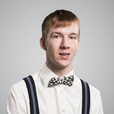 Gülümseyen hippi, mutlu ve hoş bakışlı. Duygusal kızıl çocuk mutlu bir yüz ifadesine sahip. Adamın portresi gri arka planda beyaz gömlek, papyon ve pantolon askısı takıyor..