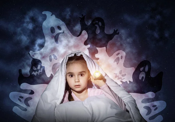 Scared girl with flashlight hiding under blanket from imaginary ghosts. Kid sitting in bed on night sky background. Covered child in pajamas not sleep at night. Mysterious phantoms in darkness.