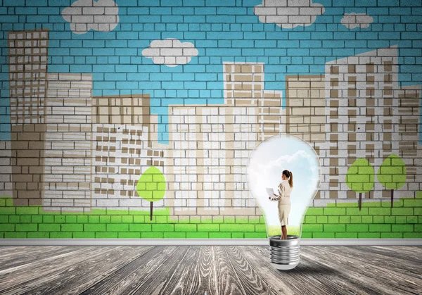 Businesswoman inside light bulb against city drawn concept