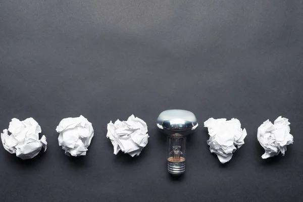 Lightbulb and crumpled white paper balls