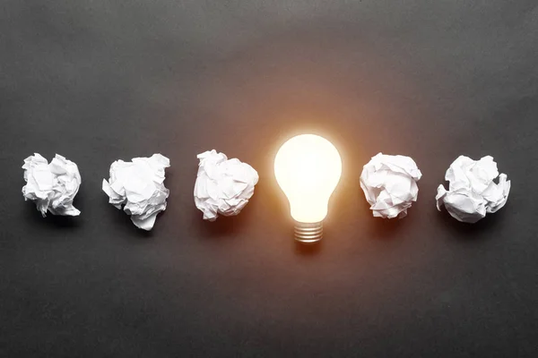 Lightbulb and crumpled white paper balls — Stock Photo, Image