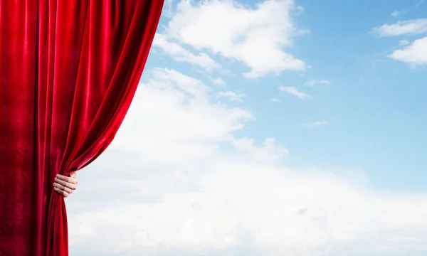 Paisagem nublada atrás de cortina vermelha e mão segurando — Fotografia de Stock