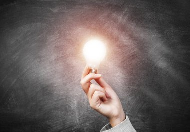 Parlayan ampulü tutan kadın.