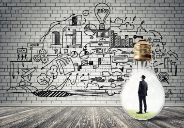 Boş beton odada ampulün içindeki iş adamı ve duvardaki çizimler