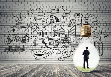 Boş beton odada ampulün içindeki iş adamı ve duvardaki çizimler