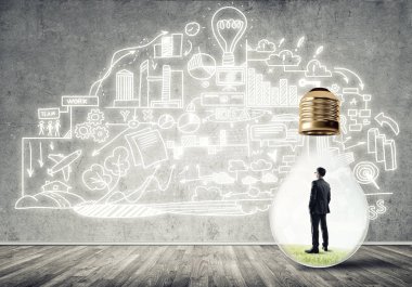 Boş beton odada ampulün içindeki iş adamı ve duvardaki çizimler