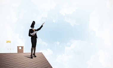 Evin çatısında baş durmak yerine kamerayla zum yapan yüzsüz iş kadını.