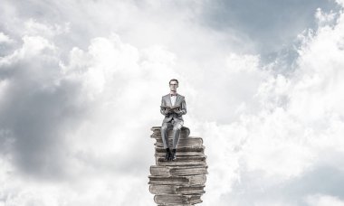 Genç işadamı ya da öğrenci mavi gökyüzünde yüzüyor ve bilim okuyor.