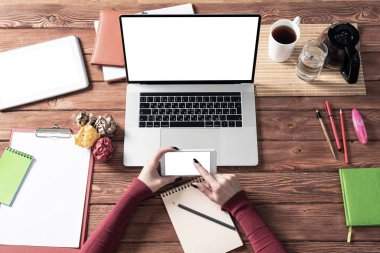 İş kadını ofis masasında akıllı telefon kullanıyor.