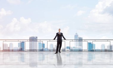 Balkonda takım elbiseli genç bir işadamı sabah şehir manzarasına karşı.