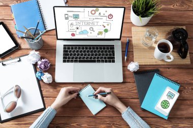 Masasında kalemle deftere yazan kadın