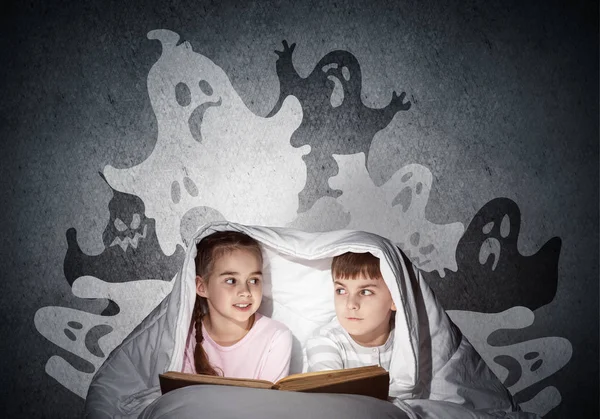 Garota assustada e menino lendo livro na cama — Fotografia de Stock
