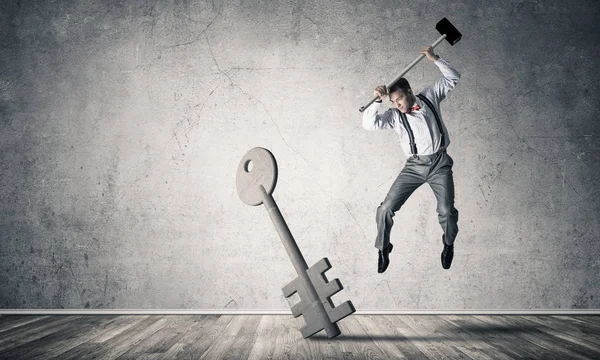 Breaking through access concept with man in room crashing concrete key — Stock Photo, Image