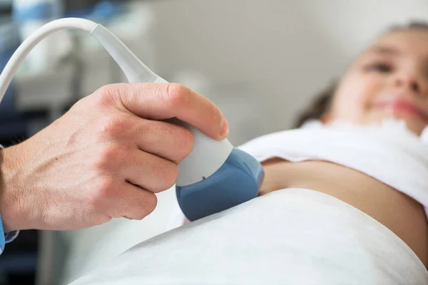 超音波機器による少女の医療検査 息子の腹部にトランスデューサを移動させます 専門の臨床診断と治療 男性の手でクローズアップ超音波スキャナ — ストック写真