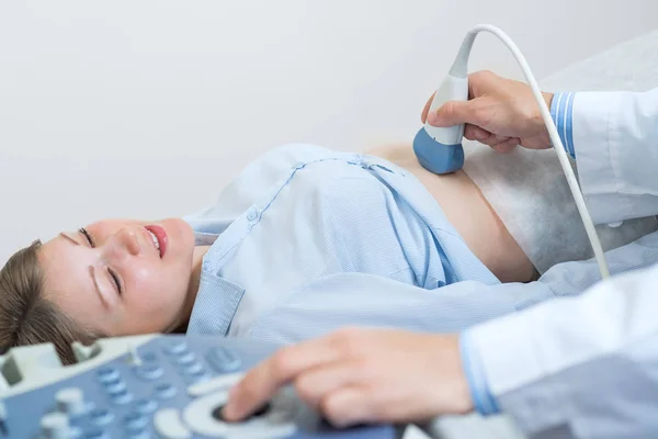 Happy woman at ultrasound examination. Prenatal diagnosis with ultrasound machine. Regular examination and disease prevention. Smiling pregnant woman visiting hospital and doing belly sonography. — Stock Image Happy Woman Ultrasound Examination Prenatal Diagnosis Ultrasound Machine Regular Examination Stock Image