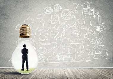 Boş beton odada ampulün içindeki iş adamı ve duvardaki çizimler