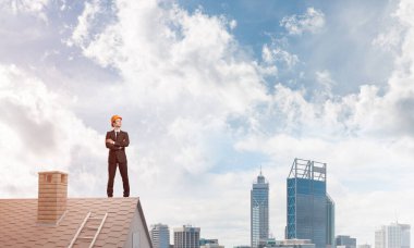 Mühendis adam çatıda dikiliyor ve başka tarafa bakıyor. Karışık ortam