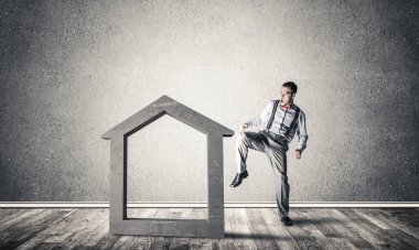 Taştan ev silueti, emlak sigortasının sembolü olarak boş odada.